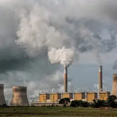 Dymiące kominy elektrowni węglowej na tle burzowych chmur. Chłodnie kominowe i budynki przemysłowe.
