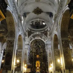 Interior de la iglesia de la Magdalena, con bóvedas ornamentadas, arcos y un retablo dorado.