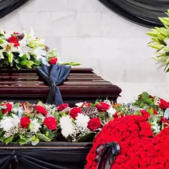 Bogata dekoracja kwiatowa na trumnie i wokół niej. Zastanawiasz się, dlaczego kwiaty po pogrzebie muszą leżeć 6 tygodni?