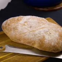 Nybakat bröd med en kniv på en skärbräda. Doften av nybakat bröd sprider sig i köket.