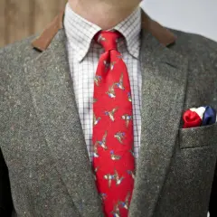 Elegancki garnitur z szarej szkockiej tkaniny wełnianej, czerwony krawat z kaczkami i chusteczka w barwach narodowych.