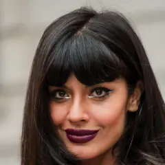 Frau mit dunklem Haar und Pony, der gerade rauswächst, und auffälligem Make-up.