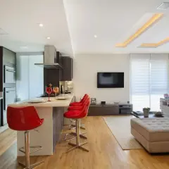 Cucina moderna con isola e sgabelli rossi, soggiorno con divano e TV. Il soffitto in cartongesso design crea un'atmosfera accogliente.
