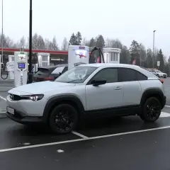 Biała Mazda MX-30 na ładowarce Ionity. Zasięg tego elektryka pozwala na spokojne podróże. Obok stacji Circle K.