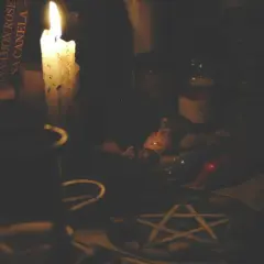 Mroczna atmosfera, płonąca świeca, książka z napisem "Cinnamon Rose", muszelki i pentagram. Czy pentagram jest zły? To zależy od intencji.