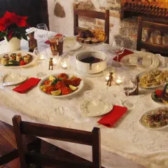 Stół wigilijny z potrawami, świecami i kominkiem w tle.