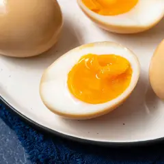 A plate of perfectly cooked onsen eggs, some whole and some halved to reveal their creamy, golden yolks.