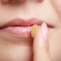 Dita applica un balsamo sulle labbra, un rimedio della nonna per labbra infiammate.