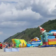 Kolorowe dmuchańce na plaży w Międzyzdrojach to świetne atrakcje dla dzieci. Wesoły klaun zaprasza do zabawy.