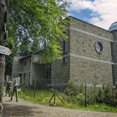 Kamienny budynek obserwatorium astronomicznego na szczycie góry. Obok tabliczka szlaku turystycznego PTTK.