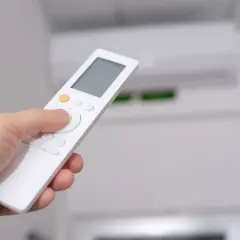 Mano sujetando control remoto para aprender como poner aire acondicionado en frio.