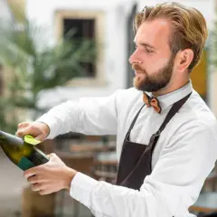 Barman przygotowuje szampana, dbając o to, by nie psuł się, zanim trafi do klienta.