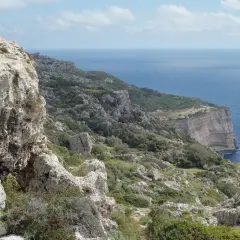 Malta's dramatic Dingli Cliffs, a rugged coastline meeting the deep blue sea under a cloudy sky.