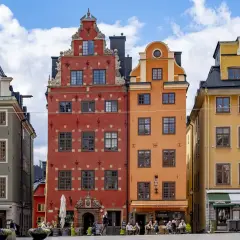 Färgglada hus på Stortorget, Stockholm sommar. En fontän står framför de gamla byggnaderna.