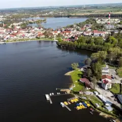 Widok z lotu ptaka na miasto Wałcz i jezioro. Widać zabudowania, lasy i przystań z łódkami. To idealne miejsce na wypoczynek nad wodą, jak podczas "blue moon wałcz".
