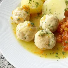 Pyszne pulpety z indyka w sosie, podane z ziemniakami i marchewką. Danie posypane świeżym koperkiem.