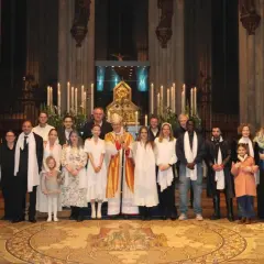 Gruppe feiert den Osternacht Gottesdienst mit Bischof in festlicher Robe vor Kerzenlicht und Altar.