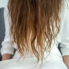 Cabello castaño, visiblemente dañado y seco, con puntas abiertas, como si fuera pelo quemado por plancha.