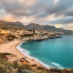 Traumhafte Bucht mit Sandstrand, türkisfarbenem Meer und einer kleinen Stadt an der Küste. Das Wetter auf Sardinien im Oktober ist hier ideal für einen Spaziergang.