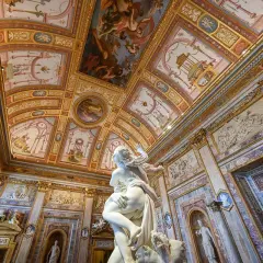 Sculpture saisissante dans une salle ornée de fresques au **jardin de la Villa Borghese**. Le plafond est un chef-d'œuvre baroque.