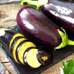 Berenjenas frescas, una cortada en rodajas, mostrando su interior amarillo. ¡Se puede comer la berenjena cruda!