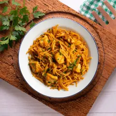 Delicioso plato de fideuà de pollo, con fideos finos y trozos de pollo tierno, decorado con perejil fresco.