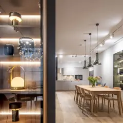 Una barra de focos ilumina la cocina y el comedor. En la estantería, lámparas decorativas y jarrones.