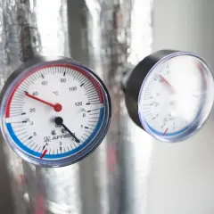 Dwa manometry na izolowanych rurach pokazują temperaturę i jakie ciśnienie wody w domu jest optymalne.
