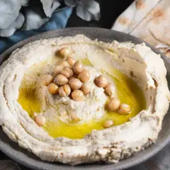 Krämig hummus med kikärtor och olivolja, perfekt för ett enkelt hummus recept. Serveras med pitabröd.