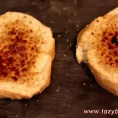 Dos rebanadas de pan tostado con azúcar caramelizada encima, listas para ser horneadas como torrijas.
