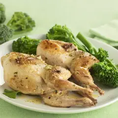 Dos codornices al ajillo doradas y jugosas, servidas con brócoli tierno y perejil fresco. Un plato delicioso y lleno de sabor.