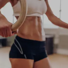 Kobieta z wyrzeźbionym brzuchem ćwiczy na kółkach gimnastycznych, przygotowując się do wyzwań crossfitu.