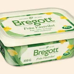 En förpackning Bregott Från Växtriket med raps-, kokos- och sheaolja. Den är 100% växtbaserad och har ett grönt mönster med gula blommor.