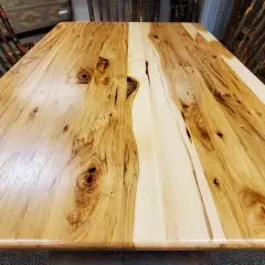 A rustic dining table crafted from the prettiest wood, showcasing natural grain patterns and knots. Chairs with twig-like legs surround it.