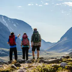 Två vandrare med ryggsäckar blickar ut över en dalgång i Abisko. En pekar mot bergen.