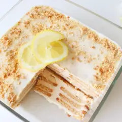 Deliciosa carlota de limón en un recipiente de vidrio, decorada con rodajas de limón y migas de galleta.