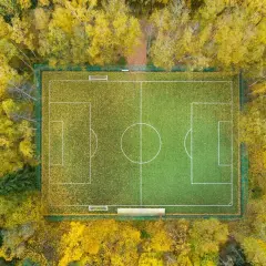 Małe boisko do piłki nożnej wymiary otoczone jesiennym lasem.