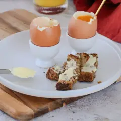 Deux oeufs à la coque, prêts à être dégustés avec des mouillettes de pain beurrées. Un petit-déjeuner simple et réconfortant.