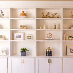 A beautifully styled built-in shelving unit showcases decorative objects, books, and framed photos.
