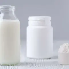 Bottiglia di latte, contenitore bianco e misurino con polvere. Le proteine del latte si trovano in questi prodotti.