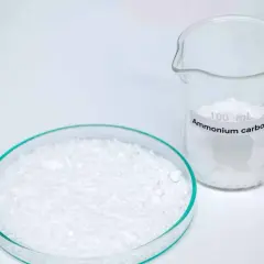 Plaque de Pétri remplie de carbonate d'ammonium blanc et un bécher gradué de 100 mL étiqueté "Ammonium carbonate".