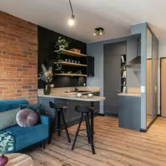 Nowoczesne mieszkanie 35m2 plan: salon z turkusową kanapą, kuchnia z wyspą i ceglaną ścianą.