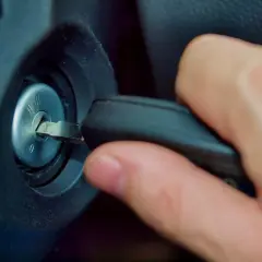 Main d'une personne insérant une clé dans le Neiman d'une voiture. Le prix du changement de Neiman est une préoccupation courante.
