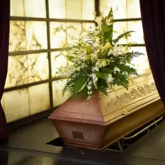 Drewniana trumna z kwiatami, przygotowana do pochówku. Śmierć Polaka za granicą to trudne procedury, ale godne pożegnanie jest ważne.