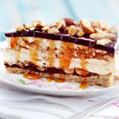 Ein Stück cremiger Käsekuchen mit Schokoladenglasur, Karamell und Nüssen als köstliches cheesecake topping.