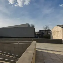 Nowoczesna architektura muzeum sztuki i techniki japońskiej Manggha z kamiennymi fasadami i zielenią w tle.