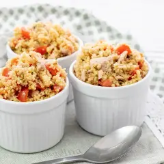 Tre coppette bianche piene di cous cous tonno e pomodorini, un piatto fresco e colorato.