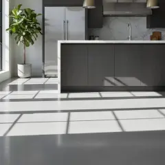 Luminosa cucina moderna con isola centrale e pavimento in resina. La luce solare crea un gioco di ombre sul pavimento, evidenziando la texture. La poliresina, materiale versatile, è ideale per pavimenti resistenti e dall'estetica contemporanea.