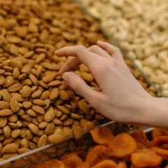 Mano seleccionando almendras para aprender como hacer harina de almendras. Se ven secas y listas para moler.