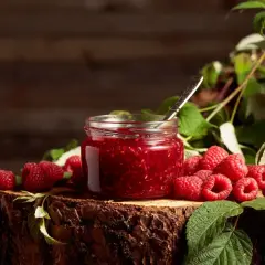 Słoik domowego dżemu malinowego i świeże maliny na pniu drzewa. Idealne, by pokazać, co zrobić z malin.
